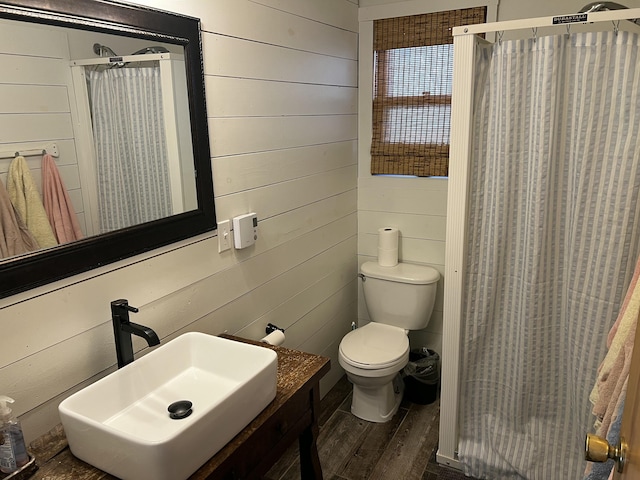 full bath featuring toilet, wood walls, a shower stall, and wood finished floors