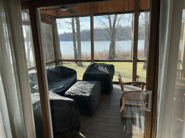 sunroom featuring a ceiling fan, a water view, and plenty of natural light