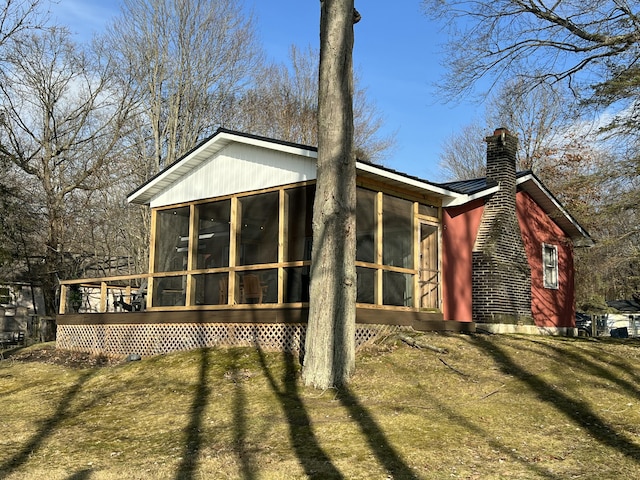 rear view of property with a sunroom, metal roof, and a lawn