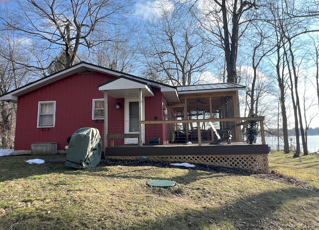 view of front of house featuring a deck, metal roof, a front lawn, and a sunroom