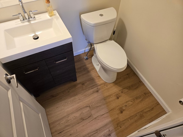 bathroom with toilet, baseboards, wood finished floors, and vanity