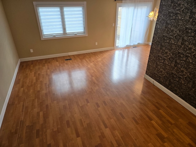 spare room featuring visible vents, baseboards, and wood finished floors