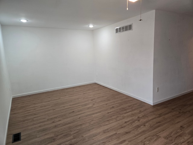 below grade area with dark wood-style flooring, visible vents, and baseboards