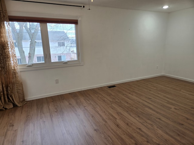 spare room featuring visible vents, baseboards, and wood finished floors