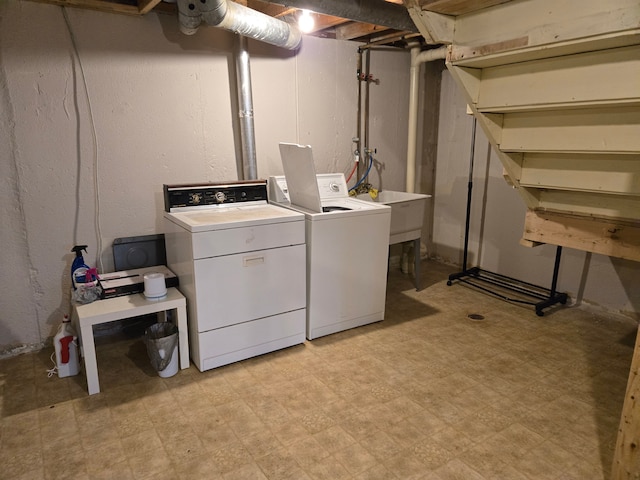 clothes washing area with a sink, light floors, washing machine and clothes dryer, and laundry area