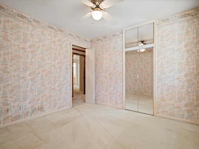 carpeted empty room featuring wallpapered walls, a ceiling fan, and baseboards