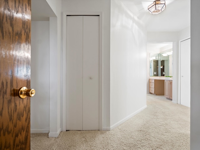 hall featuring light carpet and baseboards