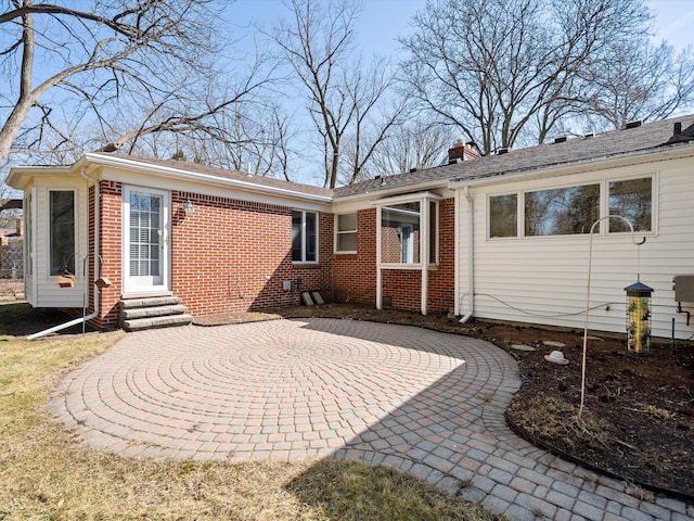 back of property featuring brick siding, a chimney, and entry steps