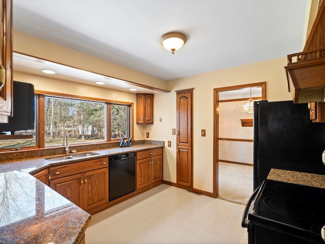 kitchen featuring baseboards, a sink, black appliances, dark countertops, and brown cabinets