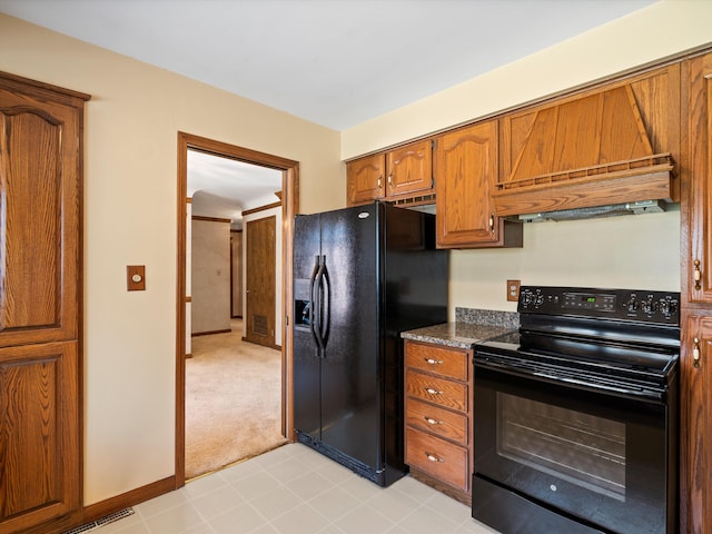 kitchen with dark countertops, baseboards, light carpet, brown cabinetry, and black appliances