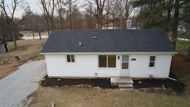 new england style home featuring roof with shingles and a chimney