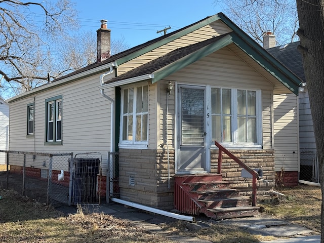 rear view of property with entry steps, a chimney, cooling unit, and fence