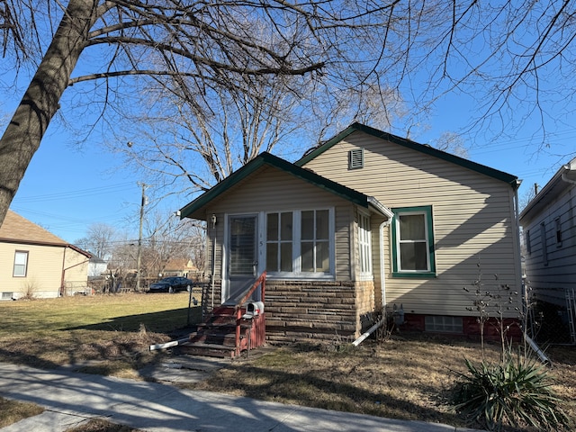 view of front of property featuring entry steps, stone siding, and a front lawn