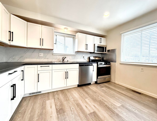 kitchen featuring tasteful backsplash, dark countertops, visible vents, appliances with stainless steel finishes, and a sink