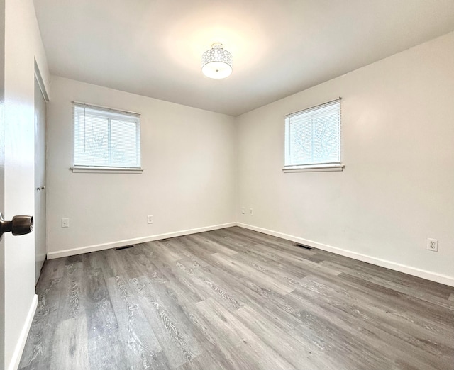 unfurnished room featuring baseboards, visible vents, and wood finished floors