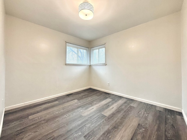 unfurnished room with baseboards and dark wood-style flooring