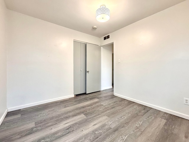 spare room featuring wood finished floors, visible vents, and baseboards