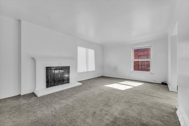 unfurnished living room featuring a fireplace with raised hearth and carpet