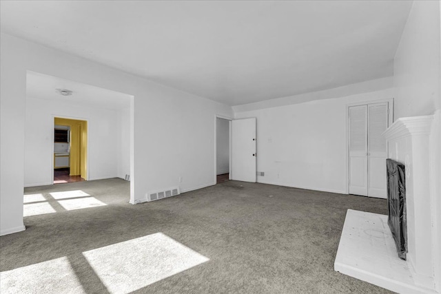 unfurnished living room featuring carpet floors, visible vents, and a fireplace