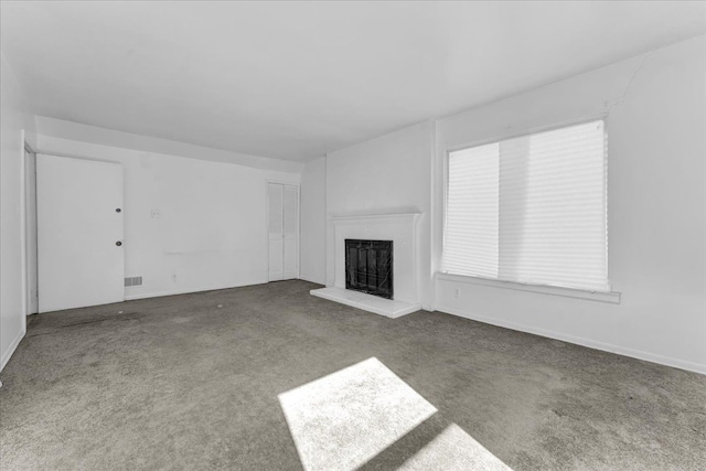 unfurnished living room with carpet floors, a fireplace with raised hearth, and visible vents