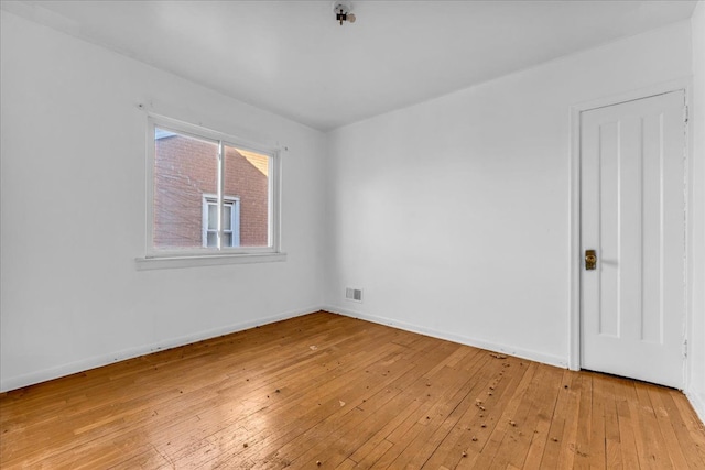 unfurnished room featuring light wood-style floors, visible vents, and baseboards