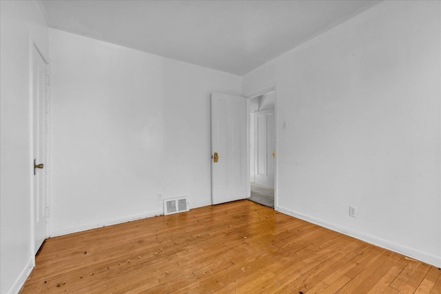 spare room featuring light wood-type flooring, baseboards, and visible vents