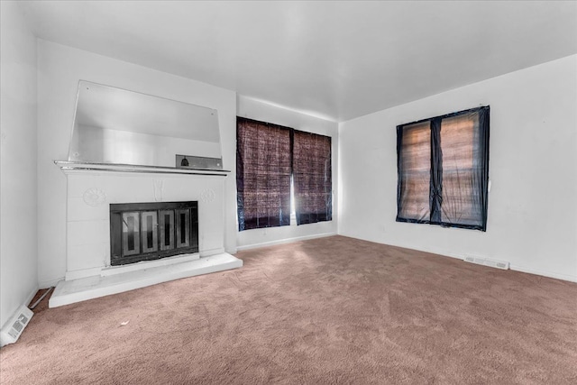 unfurnished living room featuring carpet, visible vents, and a glass covered fireplace