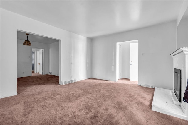 unfurnished living room featuring a fireplace with raised hearth, carpet, and visible vents