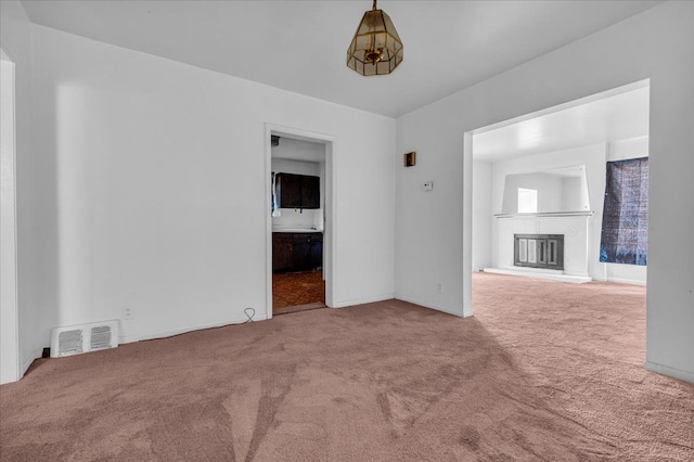 unfurnished living room with carpet, visible vents, and a glass covered fireplace