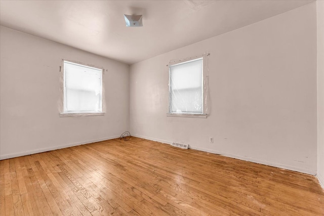 spare room featuring baseboards, visible vents, and hardwood / wood-style floors