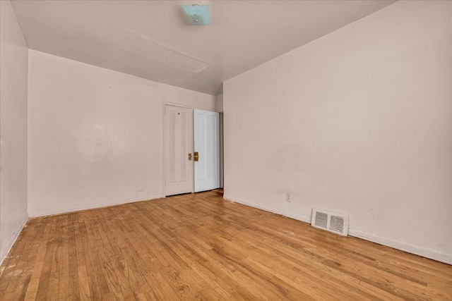 spare room featuring baseboards, visible vents, and hardwood / wood-style floors