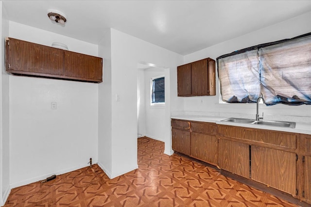 kitchen with light countertops, a sink, and baseboards