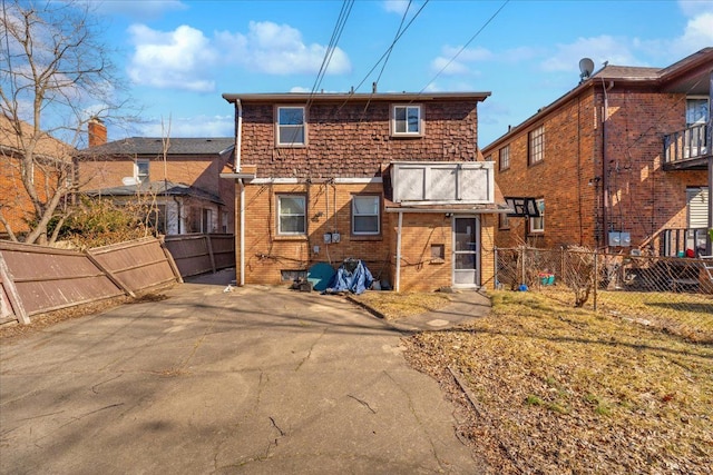 rear view of property featuring brick siding and fence