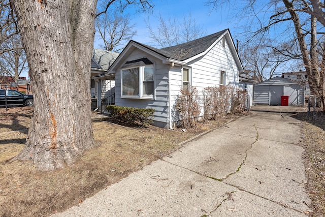 view of side of home with a garage, a shingled roof, and an outdoor structure