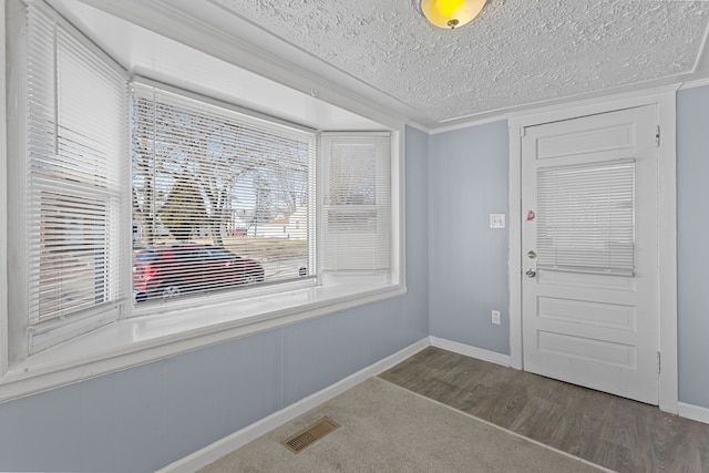 entrance foyer with crown molding, wood finished floors, visible vents, and a textured ceiling