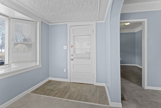 foyer with ornamental molding, a textured ceiling, wood finished floors, carpet, and baseboards