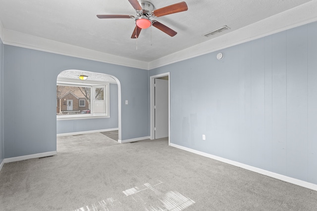 unfurnished room featuring a ceiling fan, visible vents, baseboards, arched walkways, and carpet flooring