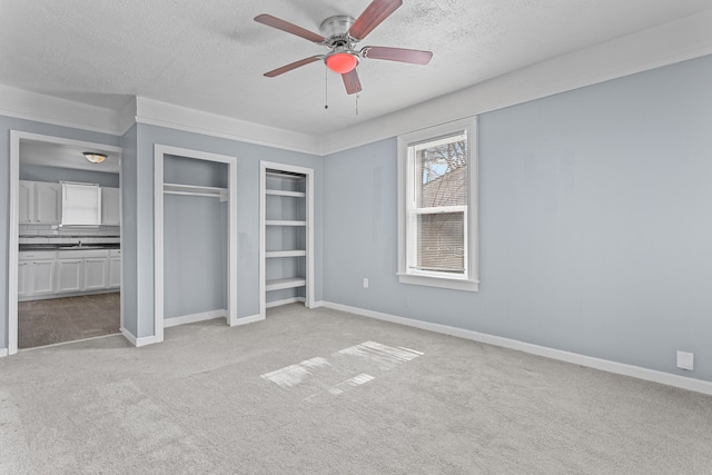 unfurnished bedroom featuring light carpet, baseboards, a textured ceiling, and a closet