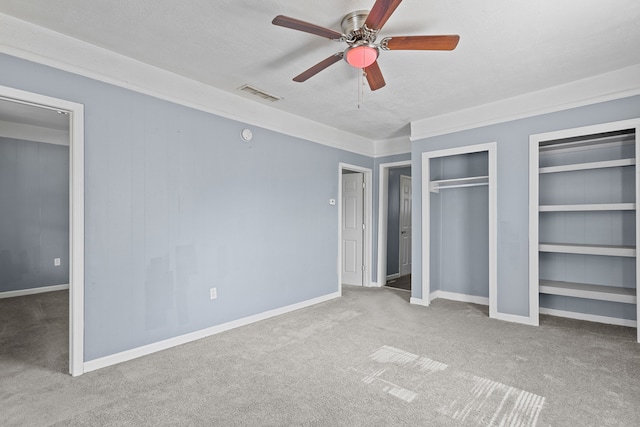 unfurnished bedroom with visible vents, ceiling fan, baseboards, multiple closets, and carpet floors