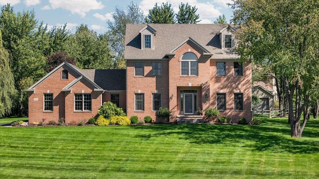 view of front of property featuring brick siding, a front yard, and a shingled roof