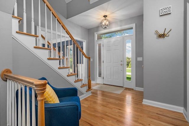 foyer featuring plenty of natural light, wood finished floors, an inviting chandelier, and baseboards