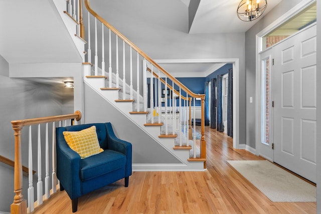 entrance foyer with a notable chandelier, wood finished floors, stairs, and baseboards