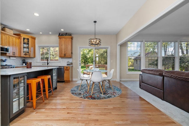 kitchen with a notable chandelier, light countertops, appliances with stainless steel finishes, decorative backsplash, and brown cabinets