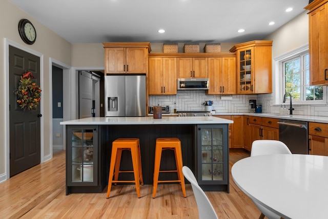 kitchen featuring stainless steel appliances, tasteful backsplash, light countertops, and a center island