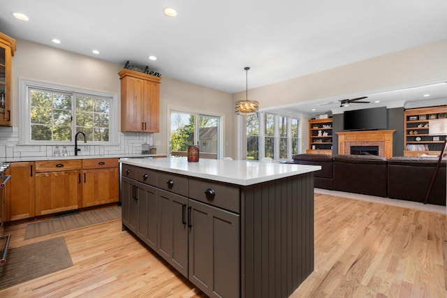 kitchen with light wood-type flooring, a fireplace, a sink, and light countertops