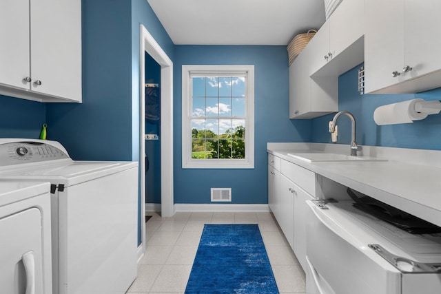 clothes washing area featuring washing machine and clothes dryer, cabinet space, visible vents, a sink, and baseboards