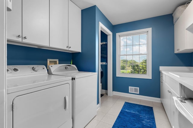 laundry area featuring washer and clothes dryer, light tile patterned floors, visible vents, cabinet space, and baseboards