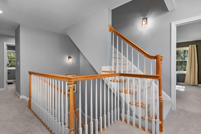 stairway featuring plenty of natural light, baseboards, and carpet flooring