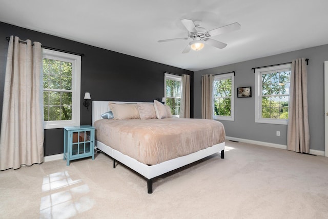 bedroom with light colored carpet, multiple windows, ceiling fan, and baseboards