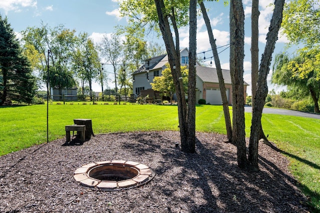 view of yard with a fire pit, an attached garage, and fence